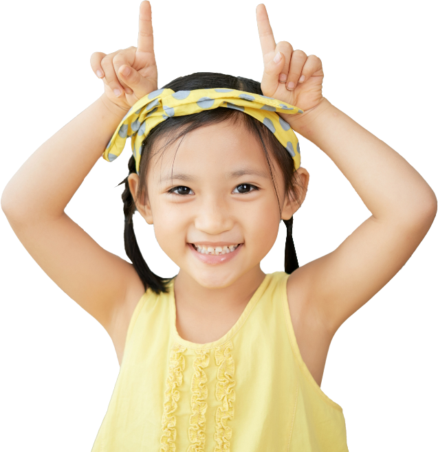 Smiling Little Chinese Girl Sitting Home Making Cow Horns Gesture